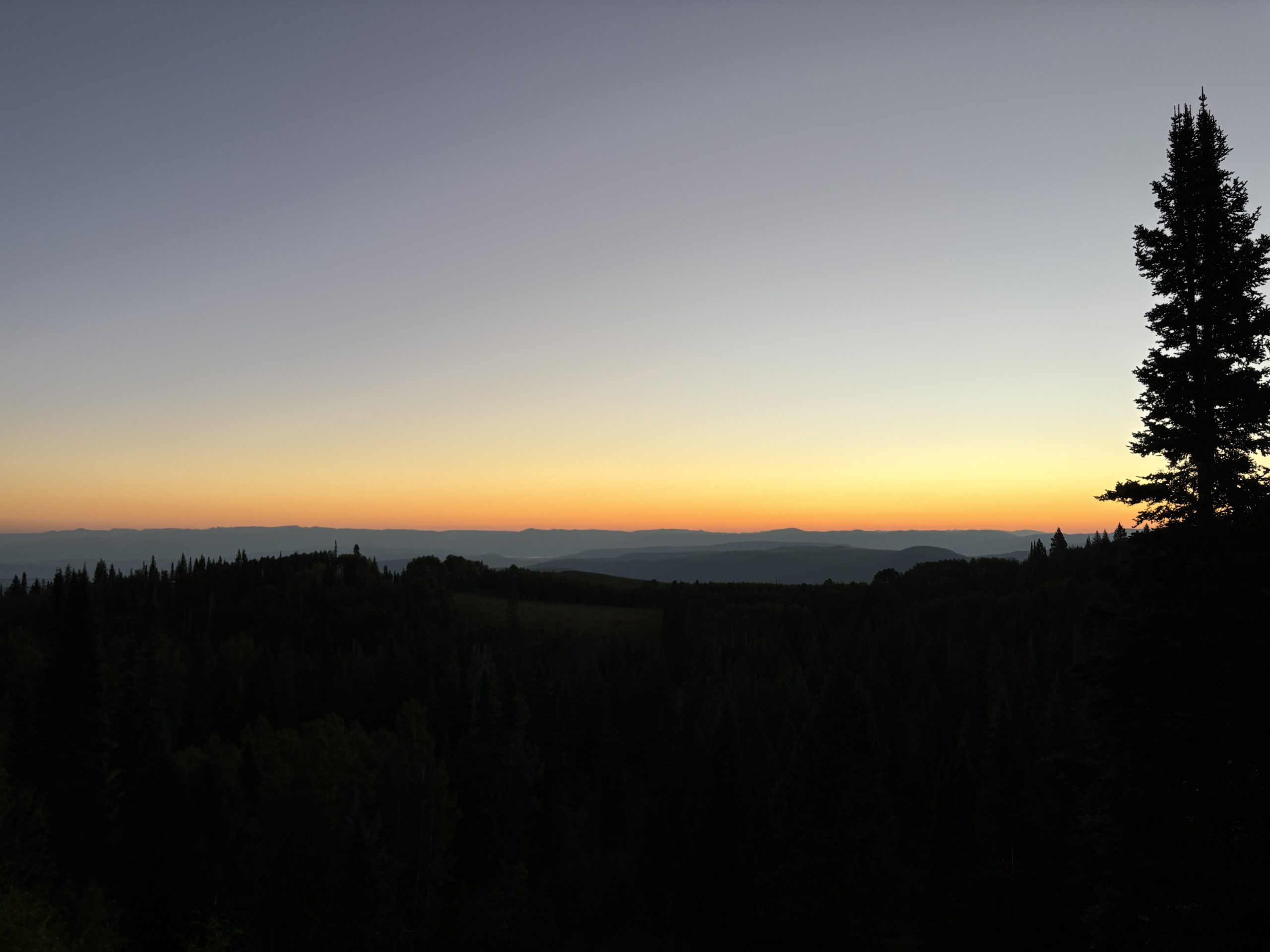 dark mountain landscape with orange and grey sunrise in the background